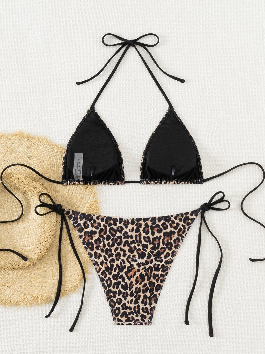 Women's black two-piece bikini set featuring a halter neck with a colorful sun pendant, triangle cups, and high-cut tie-side bottoms.