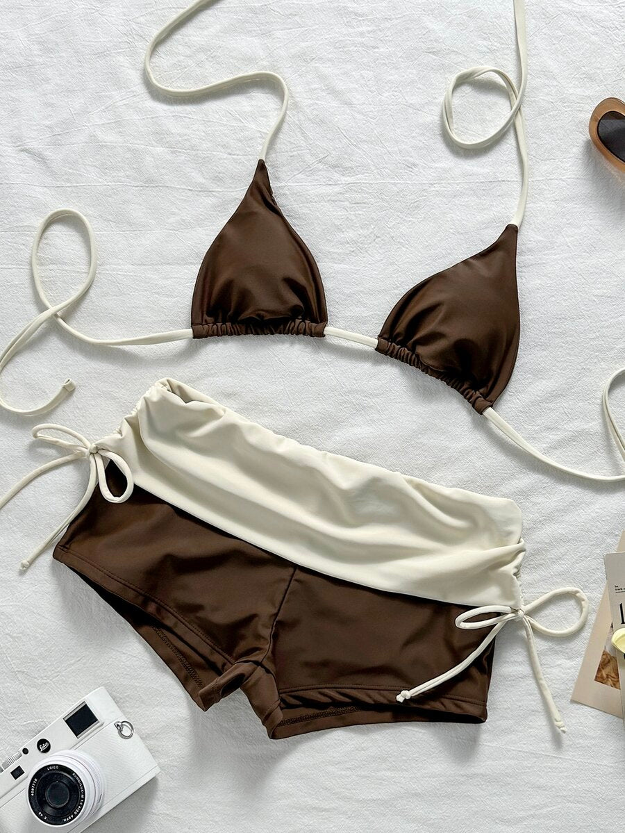 Women's halter triangle bikini top with knot detail paired with mid-waist colorblock swim shorts.