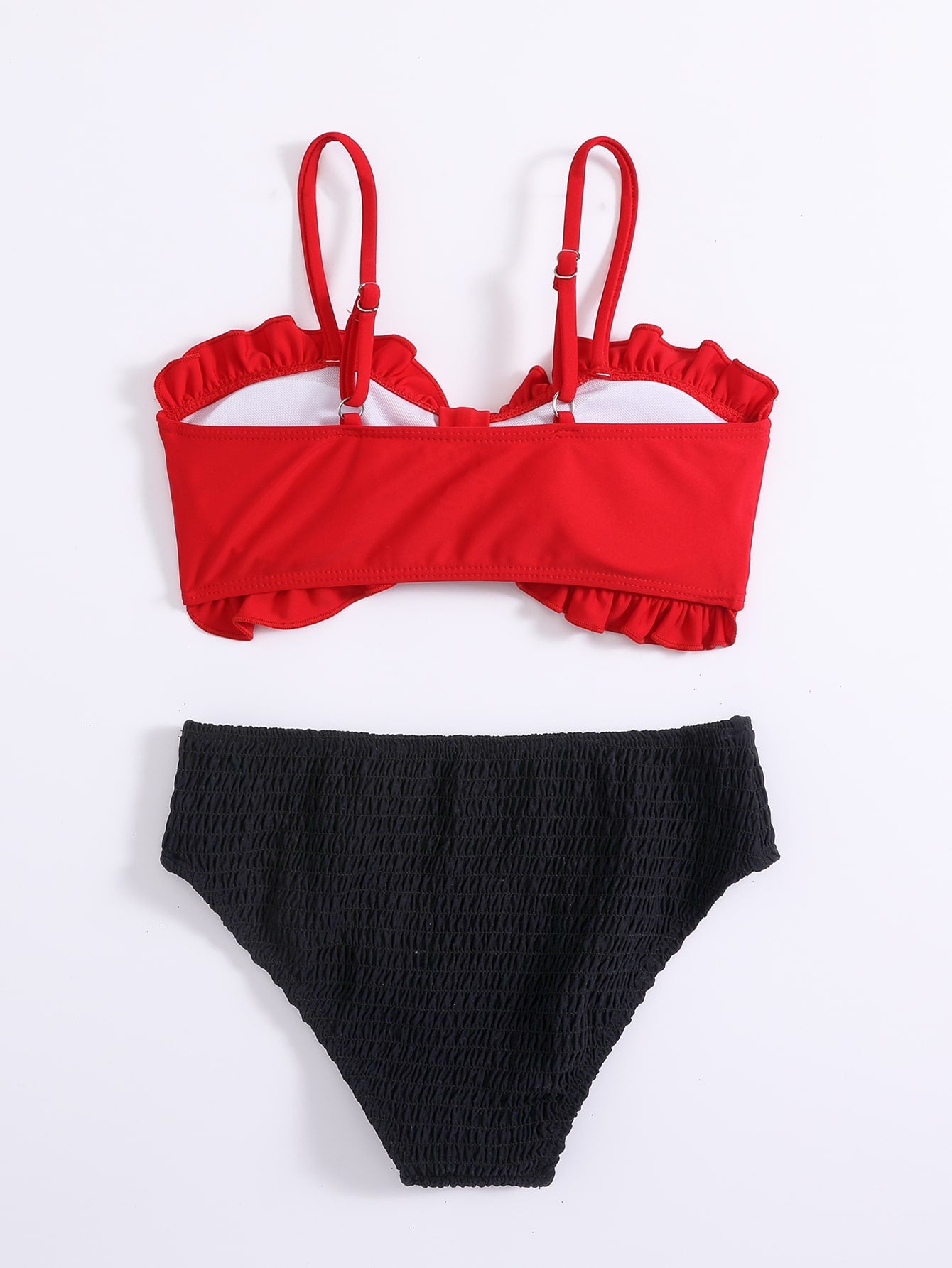 Red tween girls bikini set with a colorblock design, smocked detailing, and frill trim. Includes a wireless spaghetti strap bikini top and lined mid-waist bikini bottoms with slight stretch.