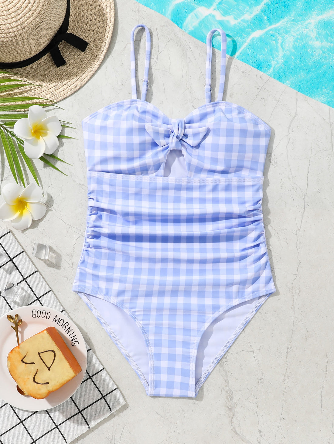 Blue and white gingham one-piece swimsuit for tween girls with cut-out detail, knot front, spaghetti straps, and lined high-stretch fabric.