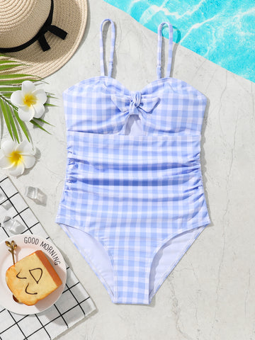 Blue and white gingham one-piece swimsuit for tween girls with cut-out detail, knot front, spaghetti straps, and lined high-stretch fabric.
