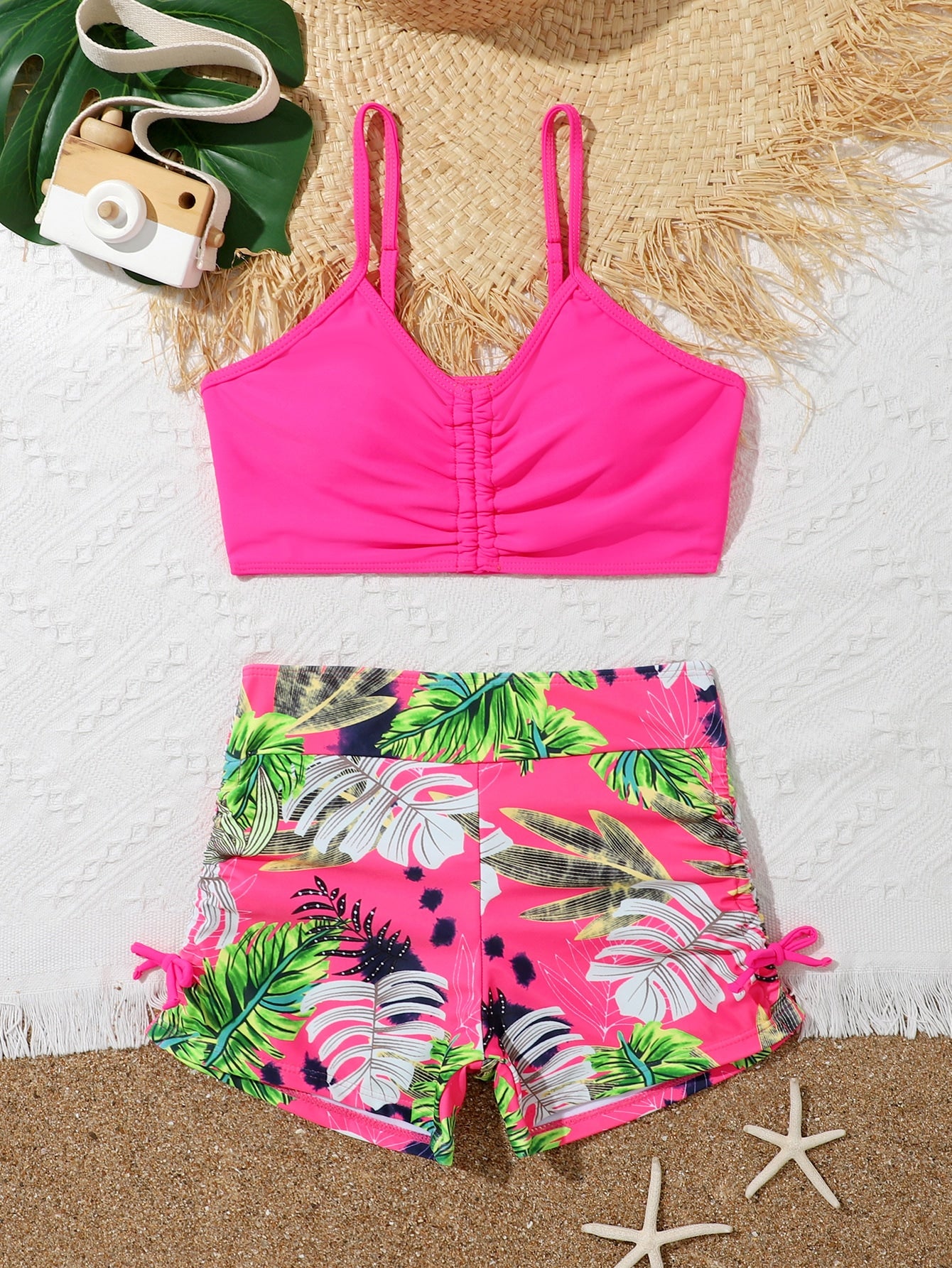 Tween girl tropical print ruched bikini set with spaghetti strap top and shorts-style bottoms, wireless design, high-stretch fabric, shown in hot pink.