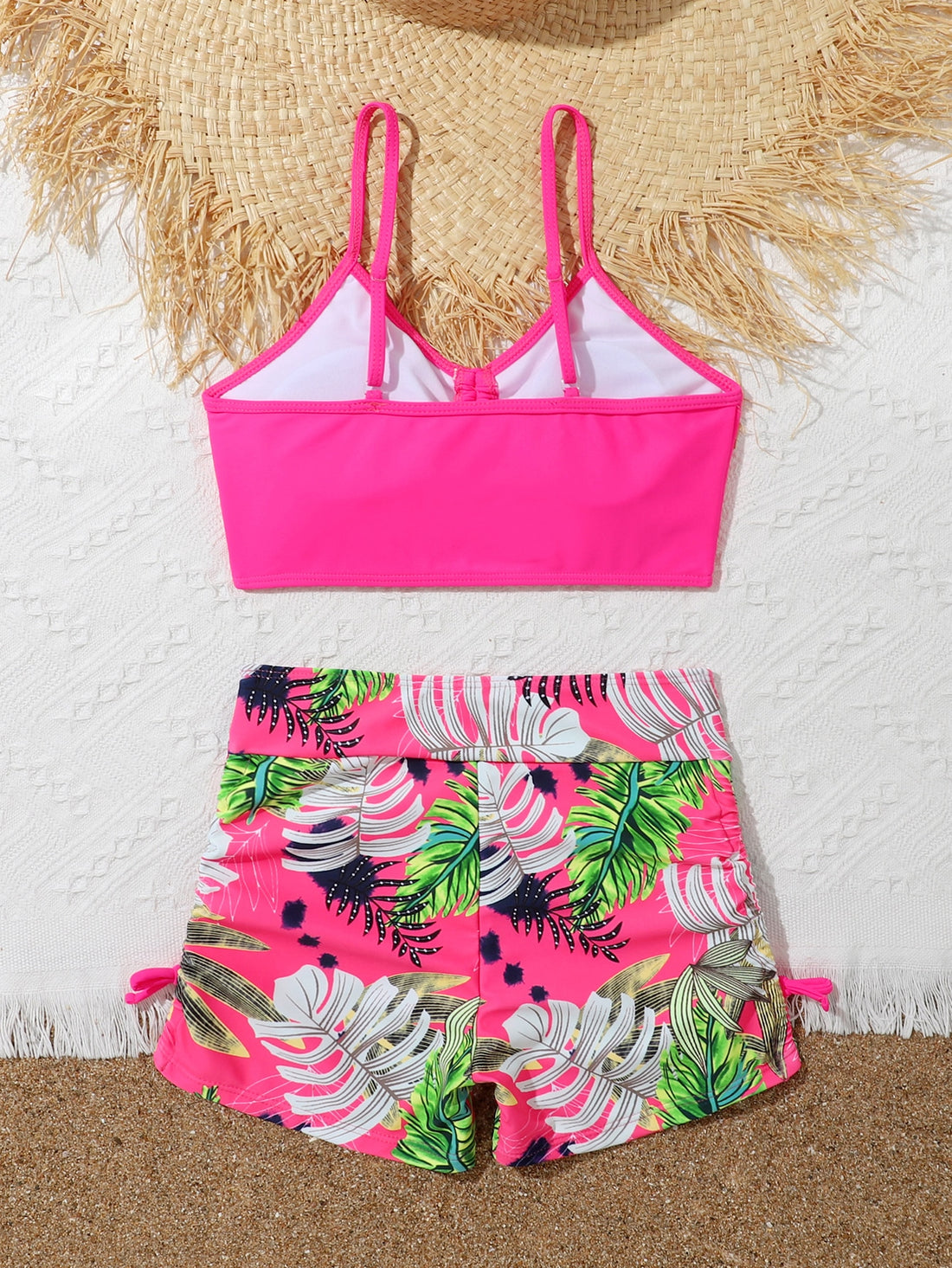 Tween girl tropical print ruched bikini set with spaghetti strap top and shorts-style bottoms, wireless design, high-stretch fabric, shown in hot pink.
