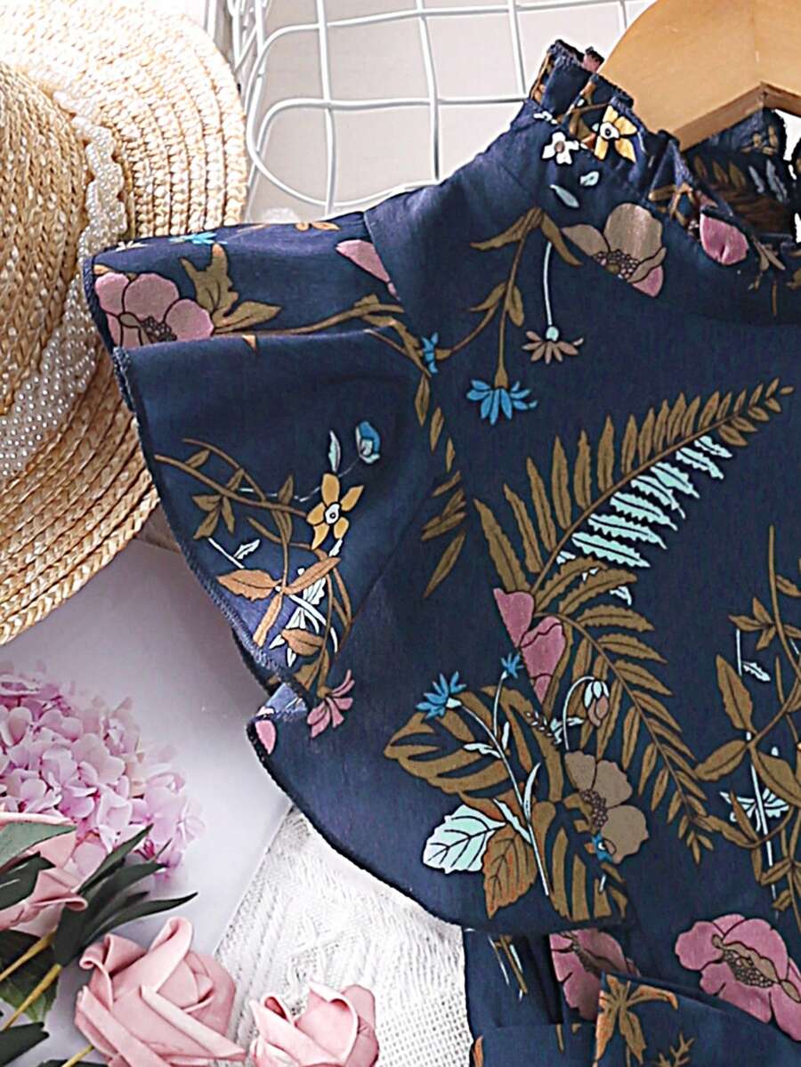 Tween girl wearing navy blue floral print ruffle trim belted pleated mini dress with stand collar and flounce cap sleeves