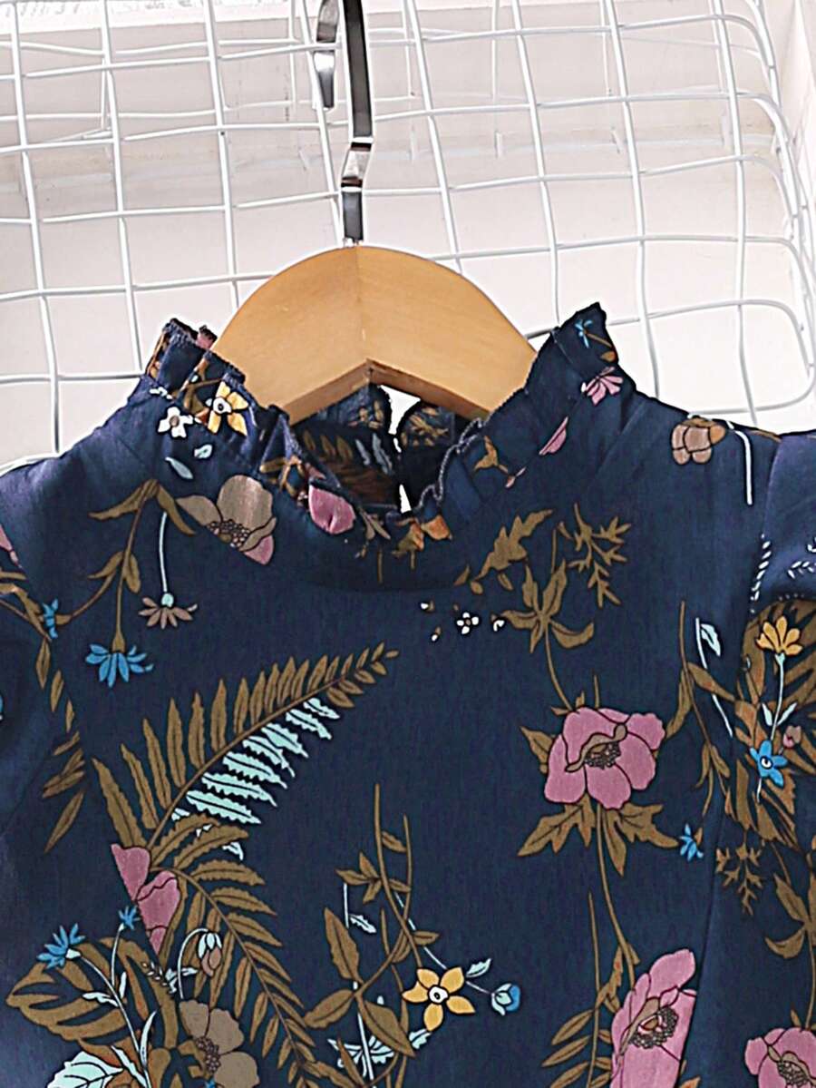 Tween girl wearing navy blue floral print ruffle trim belted pleated mini dress with stand collar and flounce cap sleeves