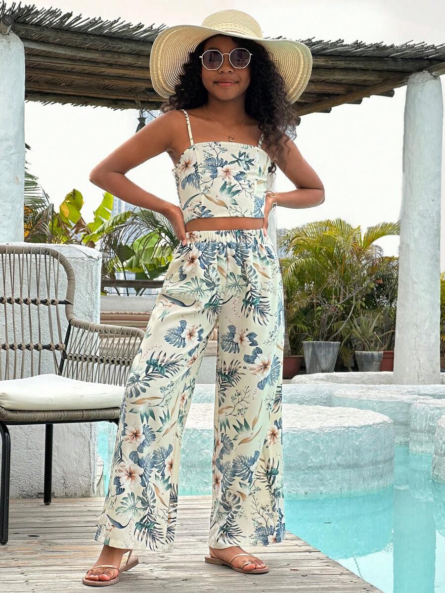 Tween girl wearing a black sleeveless spaghetti strap camisole top with 3D bow decor and matching leopard print wide leg long pants.