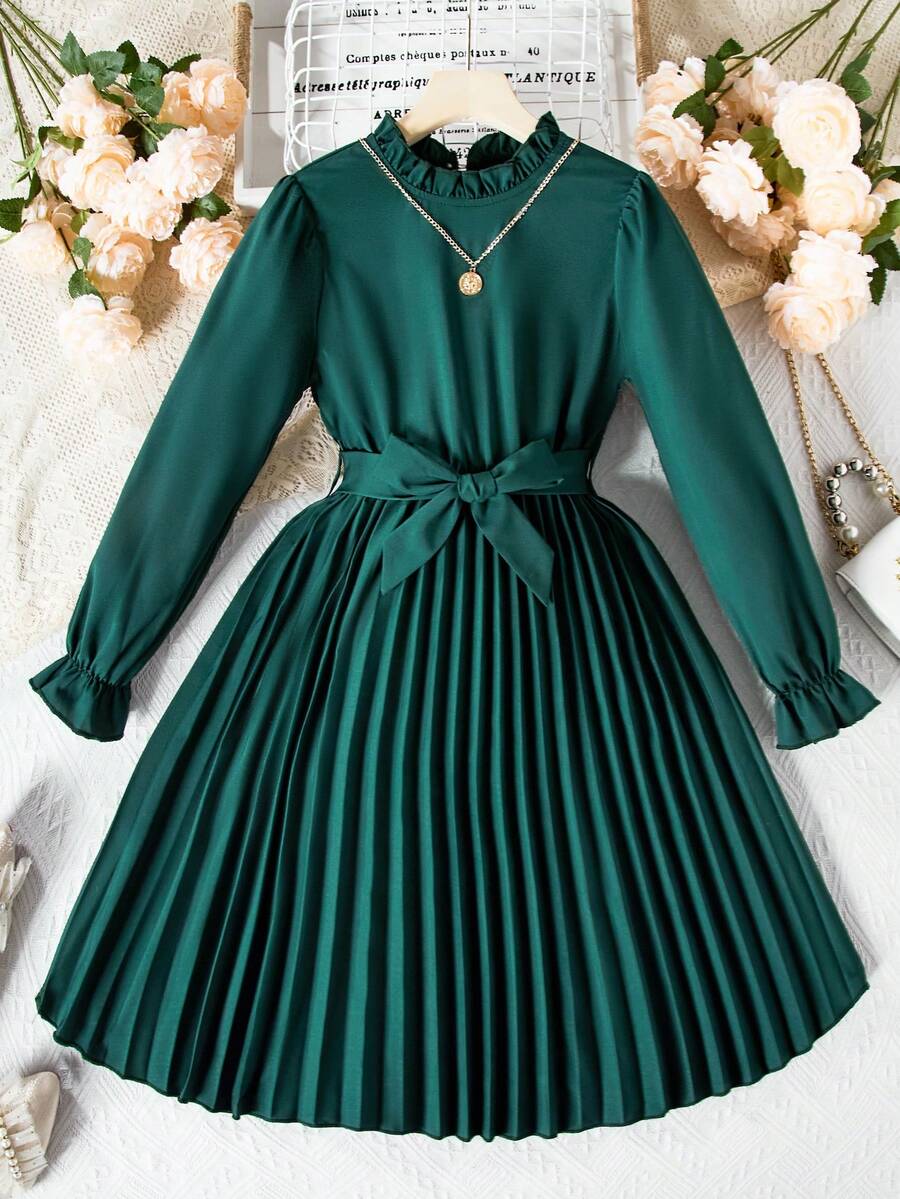Tween girl wearing a royal blue long sleeve pleated casual A-line dress featuring a stand collar, flare sleeves, high waist with front tie belt, and ruffle hem.