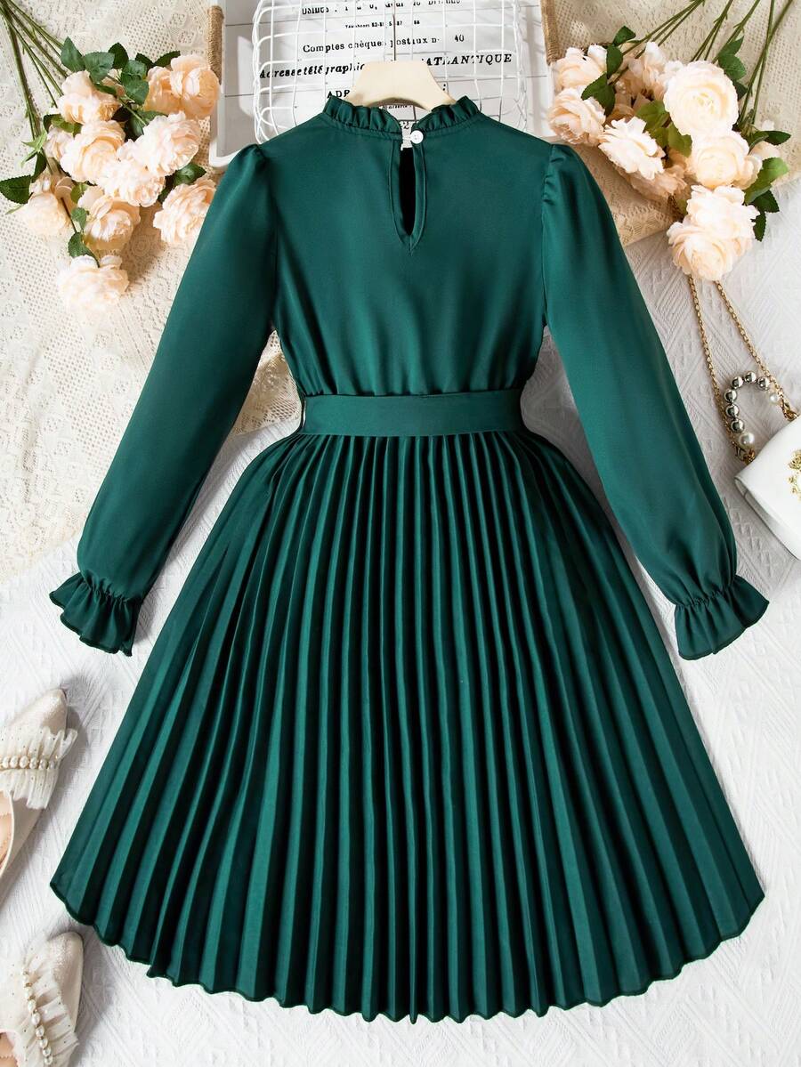 Tween girl wearing a royal blue long sleeve pleated casual A-line dress featuring a stand collar, flare sleeves, high waist with front tie belt, and ruffle hem.