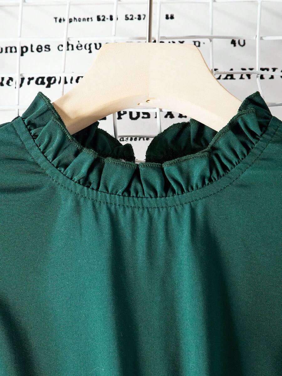 Tween girl wearing a royal blue long sleeve pleated casual A-line dress featuring a stand collar, flare sleeves, high waist with front tie belt, and ruffle hem.