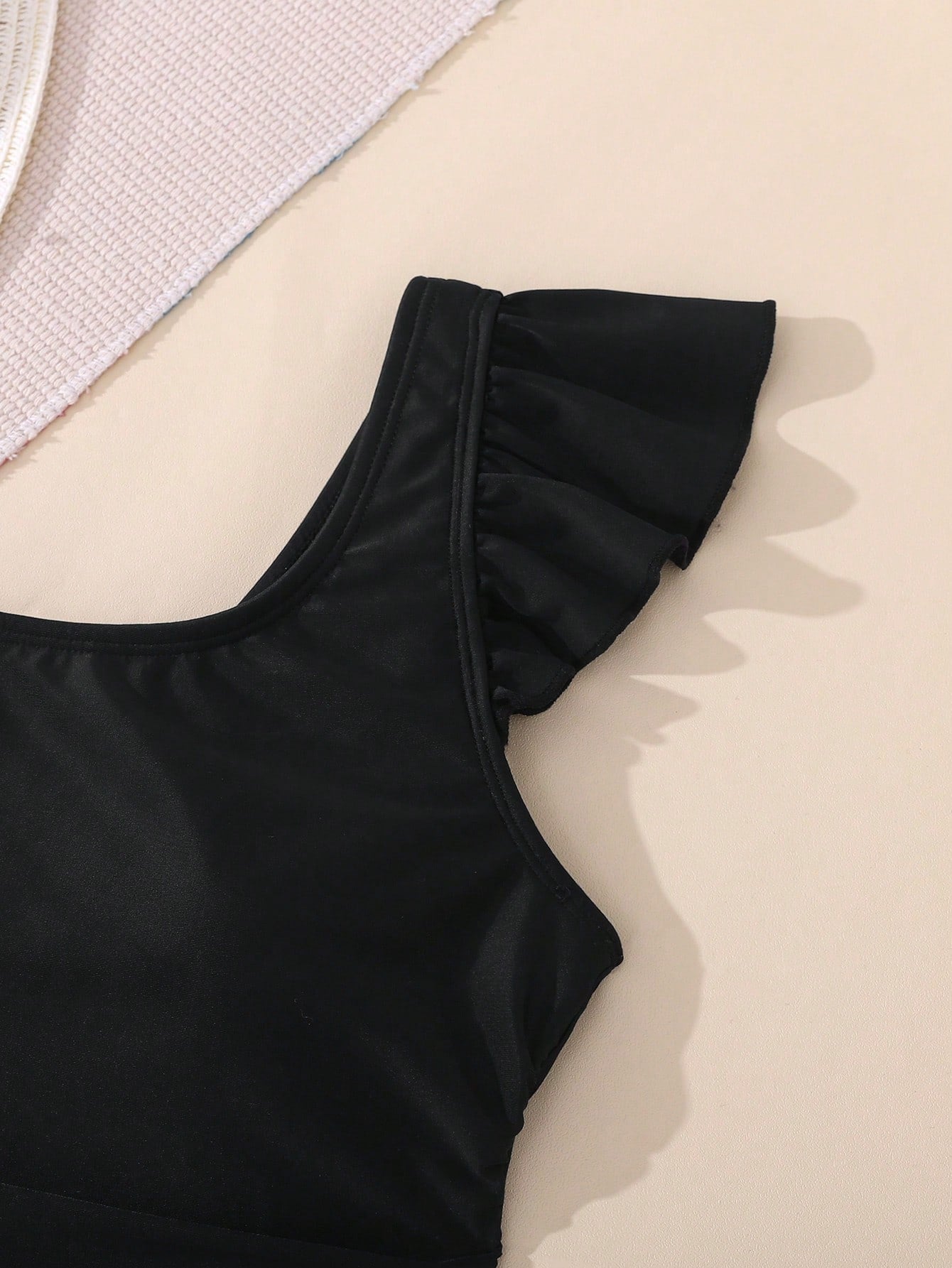Tween girl one-piece swimsuit in brown polka dot geometric print with asymmetrical neckline, ruffle detail, cut-out design, and fitted mid-waist swim bottom.
