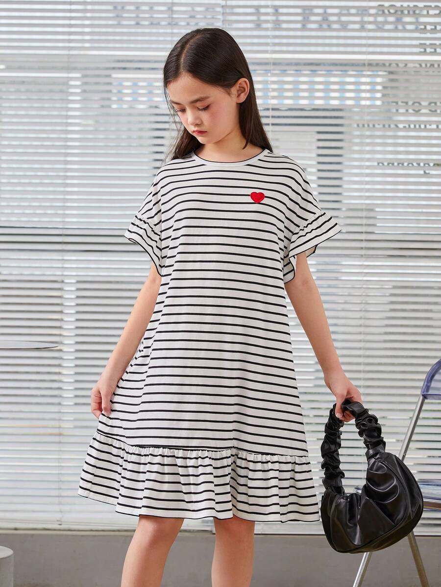 Black and white tween girls smock dress featuring a round neck, heart pattern, embroidered details, and a flounce hem.