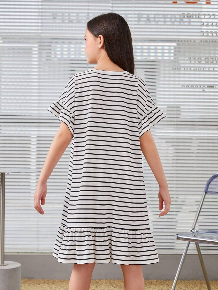 Black and white tween girls smock dress featuring a round neck, heart pattern, embroidered details, and a flounce hem.