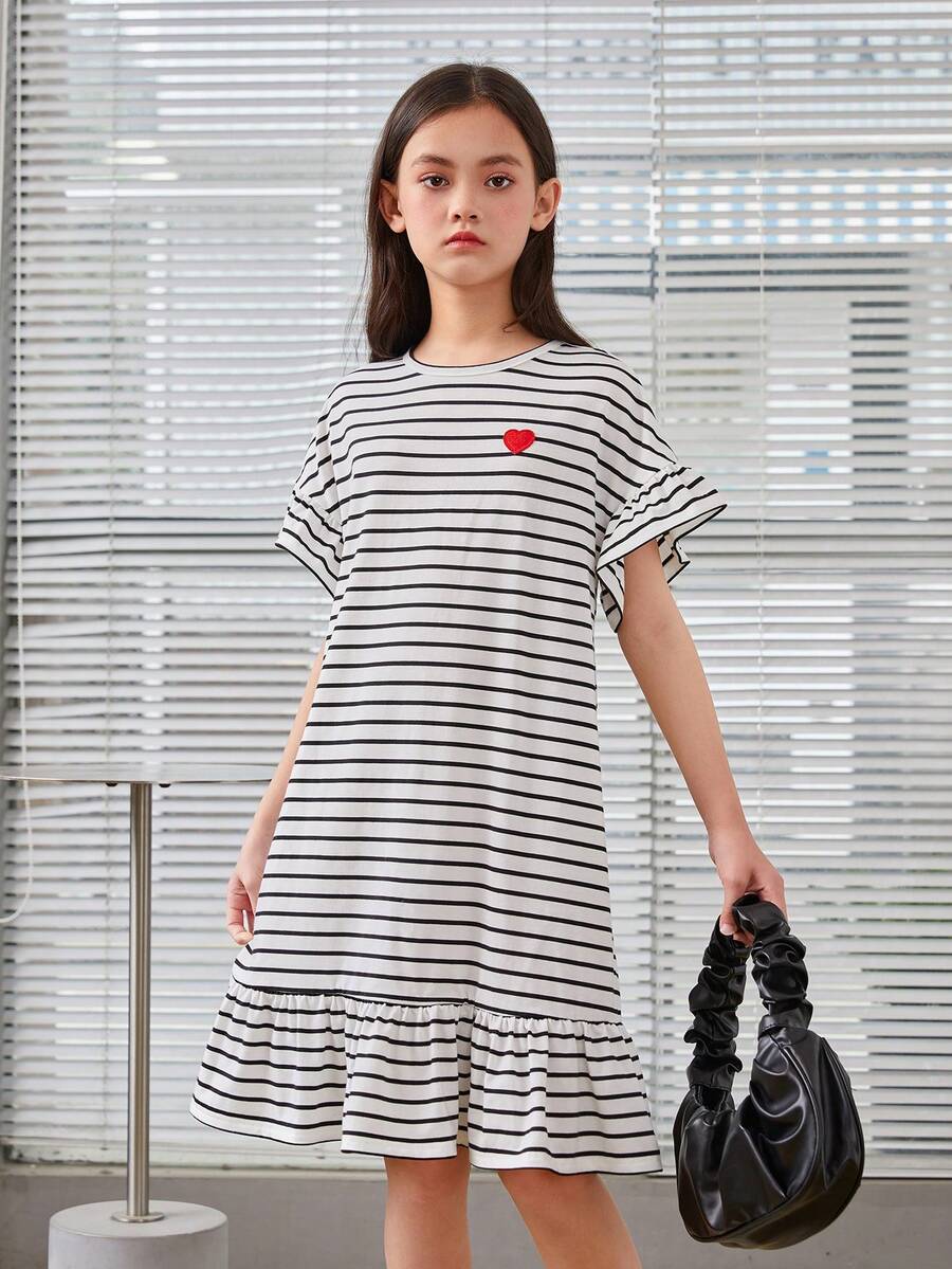 Black and white tween girls smock dress featuring a round neck, heart pattern, embroidered details, and a flounce hem.