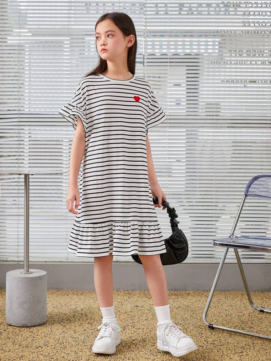 Black and white tween girls smock dress featuring a round neck, heart pattern, embroidered details, and a flounce hem.