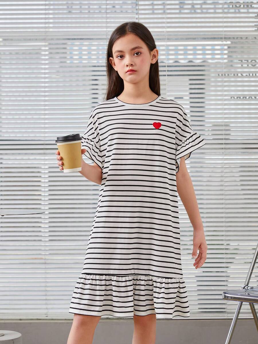 Black and white tween girls smock dress featuring a round neck, heart pattern, embroidered details, and a flounce hem.