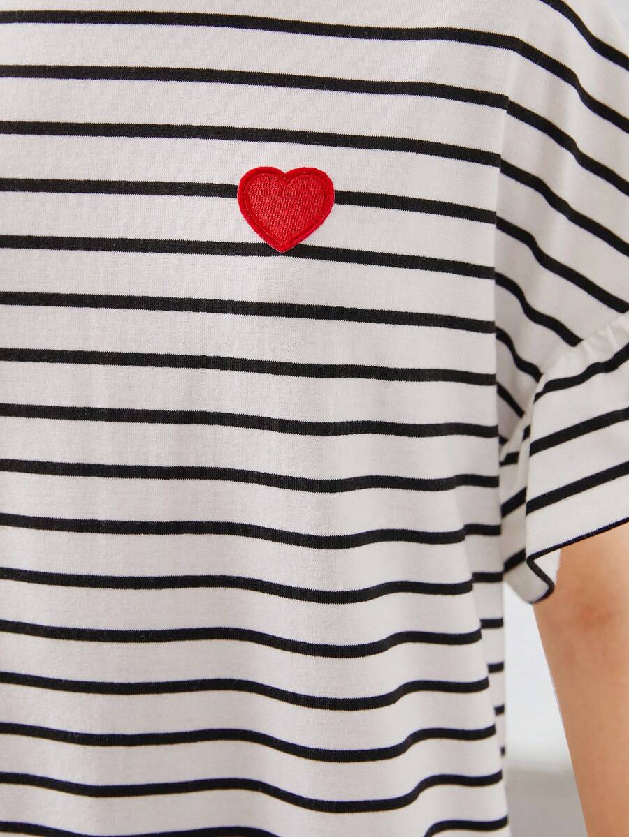 Black and white tween girls smock dress featuring a round neck, heart pattern, embroidered details, and a flounce hem.