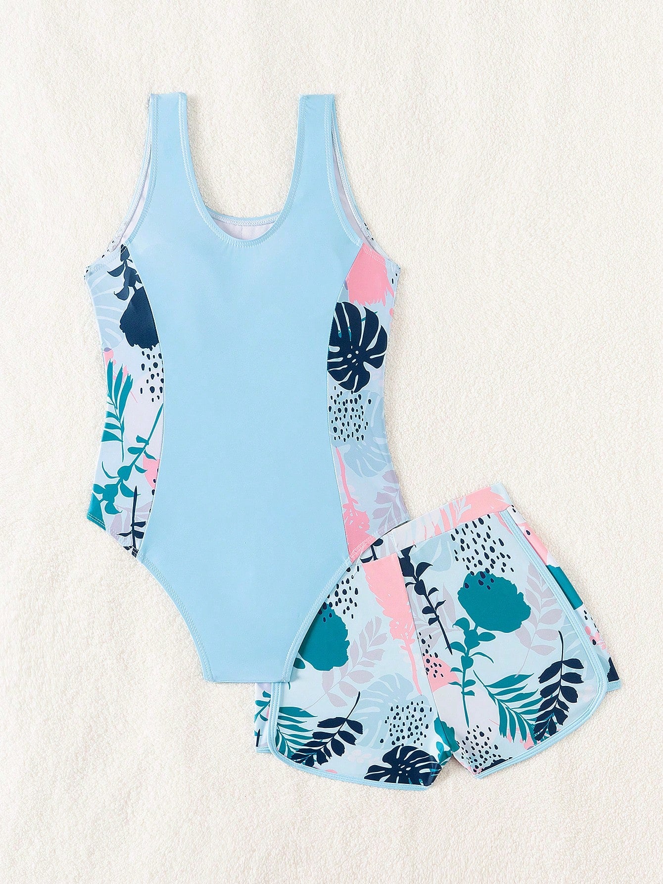 Tween girls 2-piece swimsuit set with a printed one-piece featuring ruffle trim, scoop neckline, cut-out detail, and matching shorts bottom.