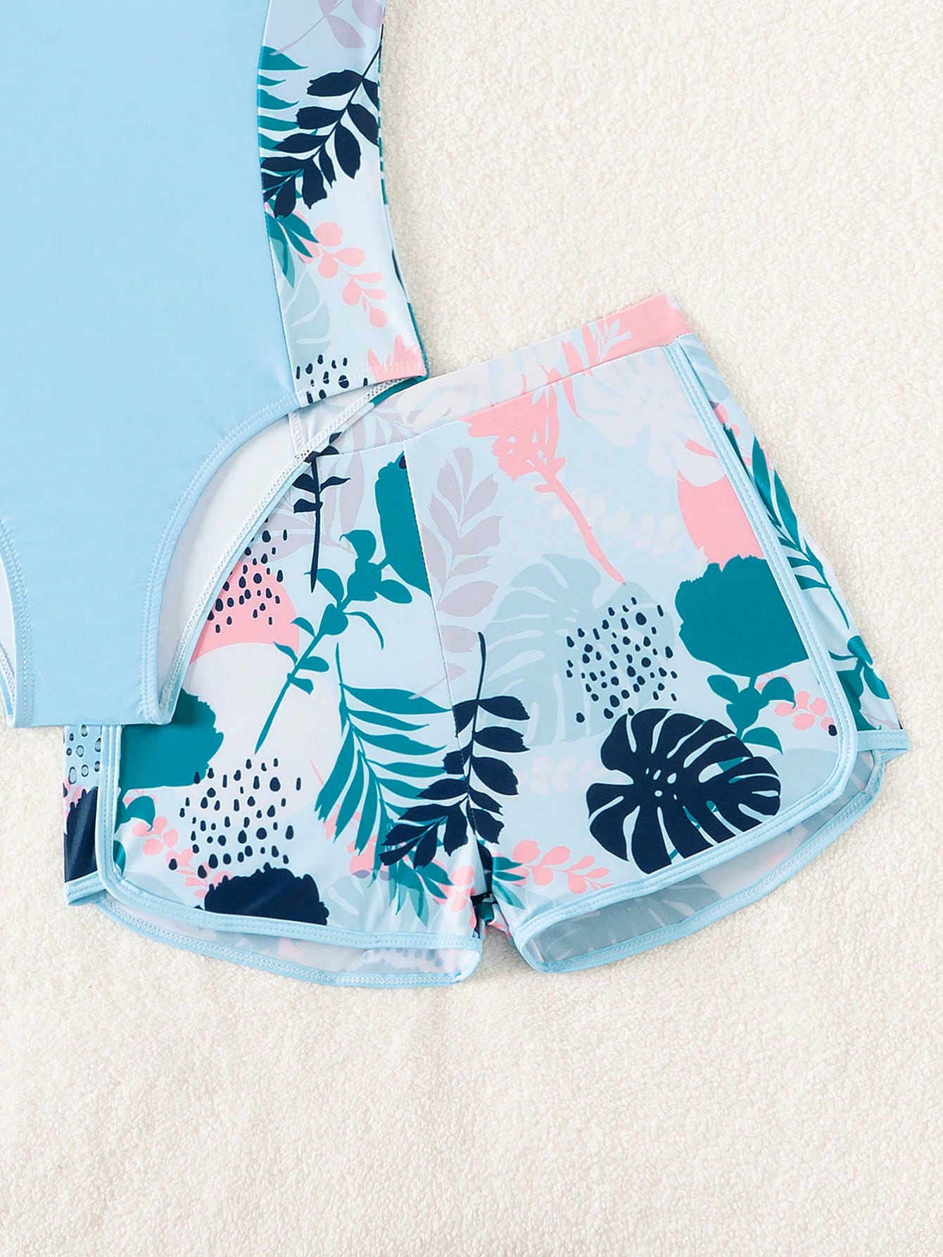 Tween girls 2-piece swimsuit set with a printed one-piece featuring ruffle trim, scoop neckline, cut-out detail, and matching shorts bottom.
