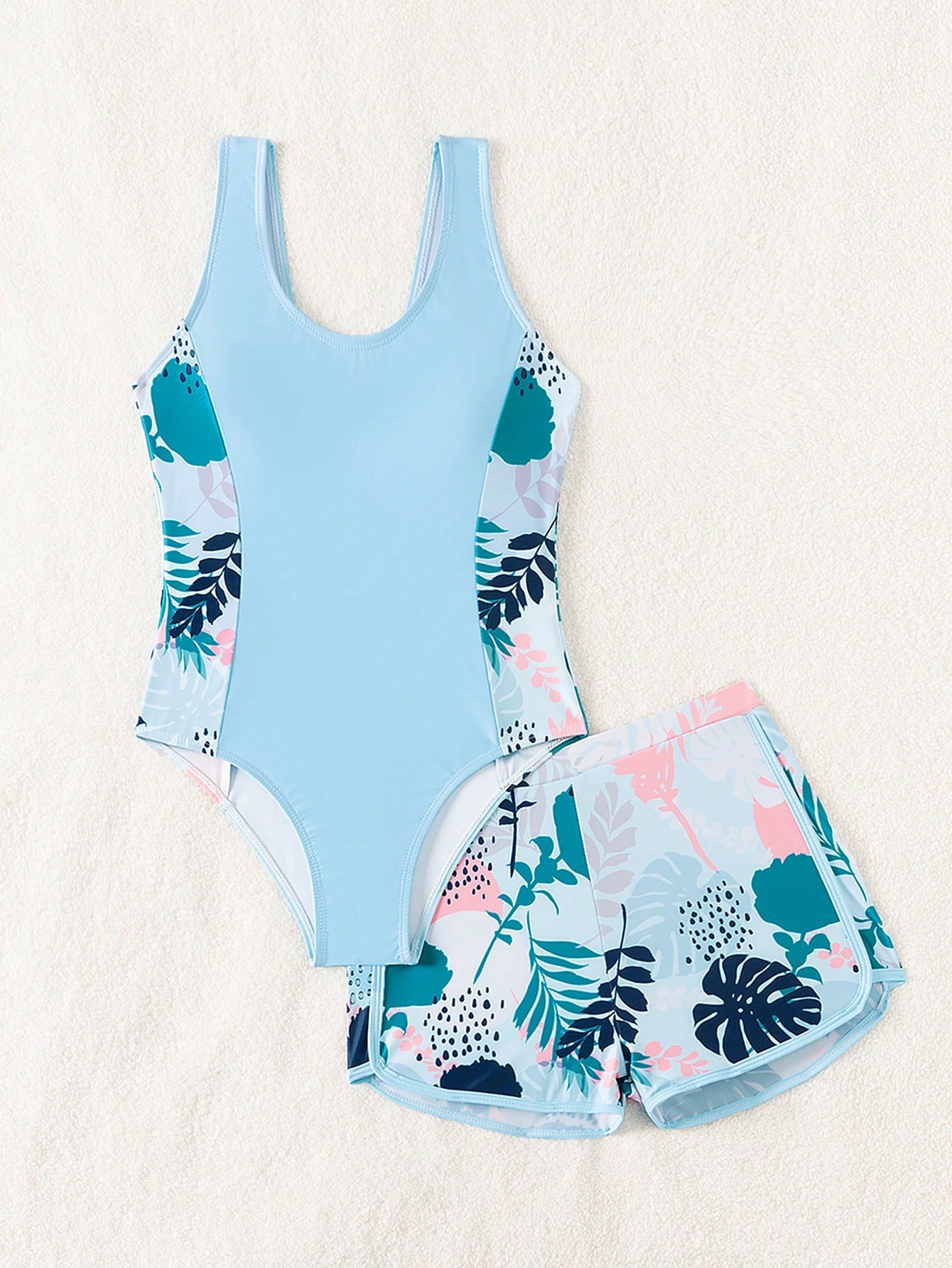 Tween girls 2-piece swimsuit set with a printed one-piece featuring ruffle trim, scoop neckline, cut-out detail, and matching shorts bottom.