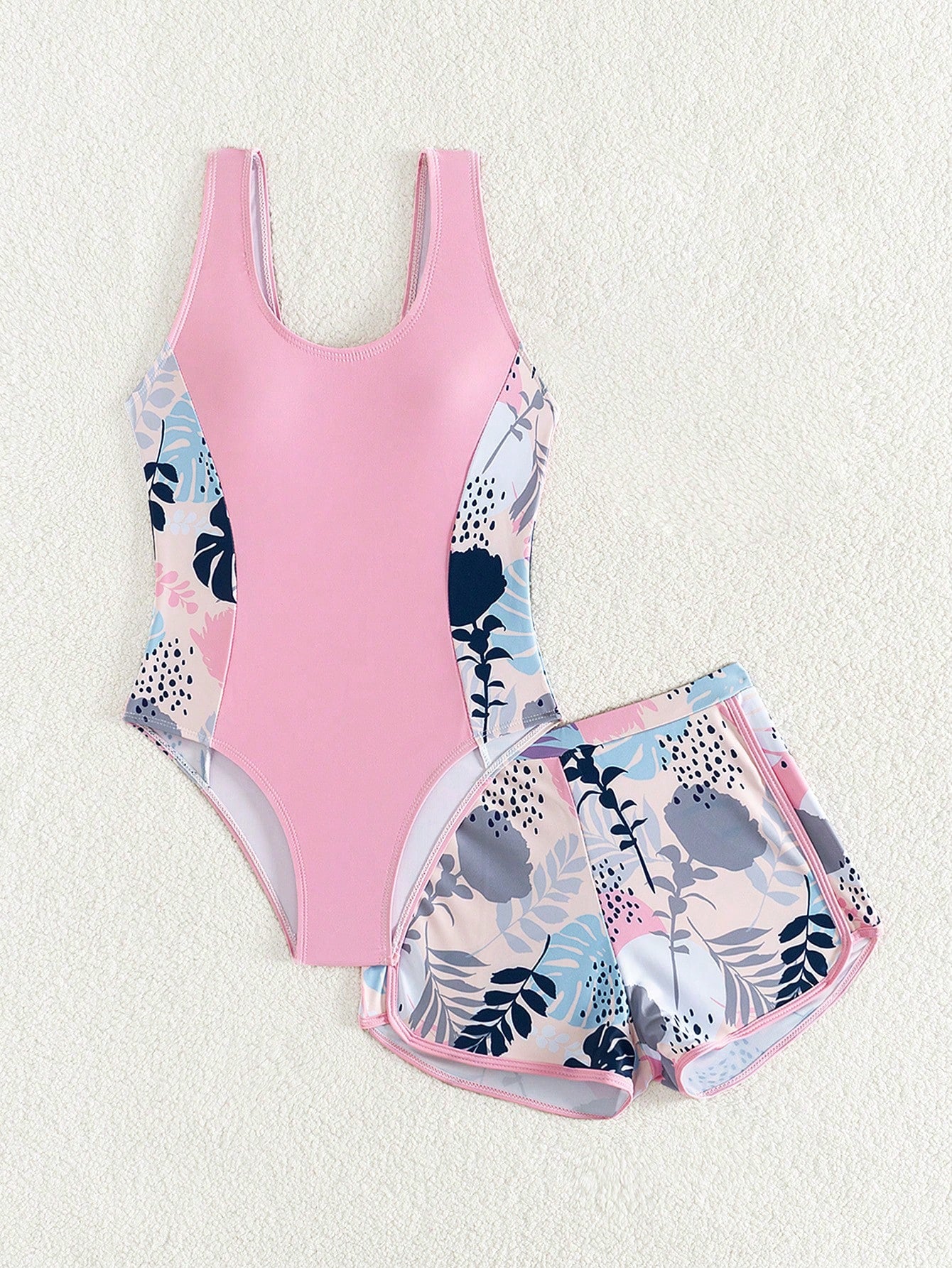 Tween girls 2-piece swimsuit set with a printed one-piece featuring ruffle trim, scoop neckline, cut-out detail, and matching shorts bottom.