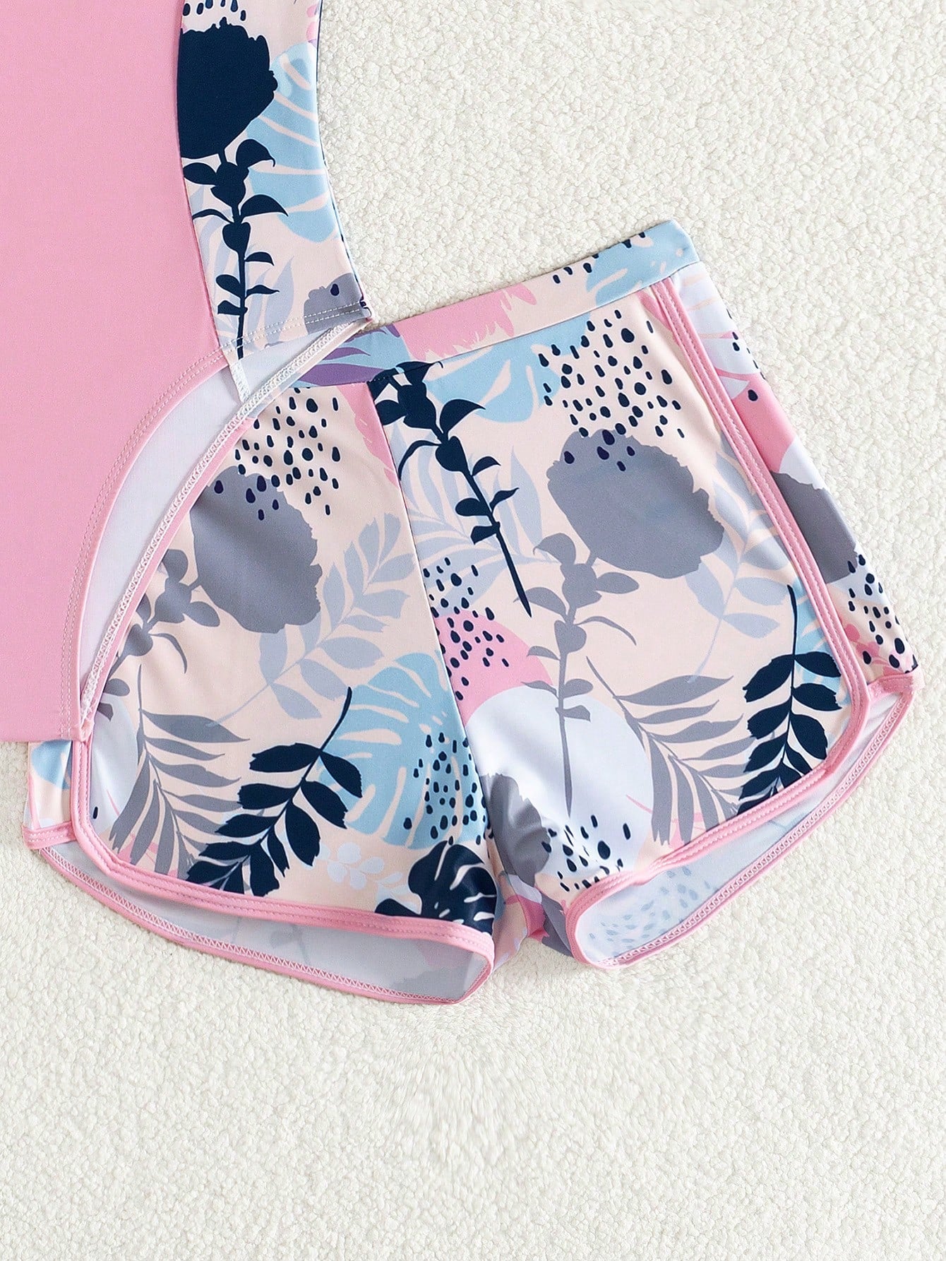 Tween girls 2-piece swimsuit set with a printed one-piece featuring ruffle trim, scoop neckline, cut-out detail, and matching shorts bottom.
