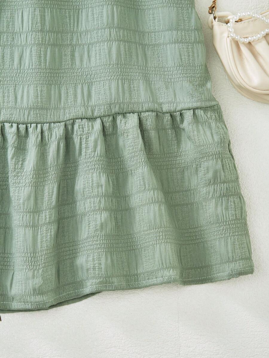 Tween girl wearing an Army Green textured short sleeve smock midi dress with round neck and ruffle flounce hem.