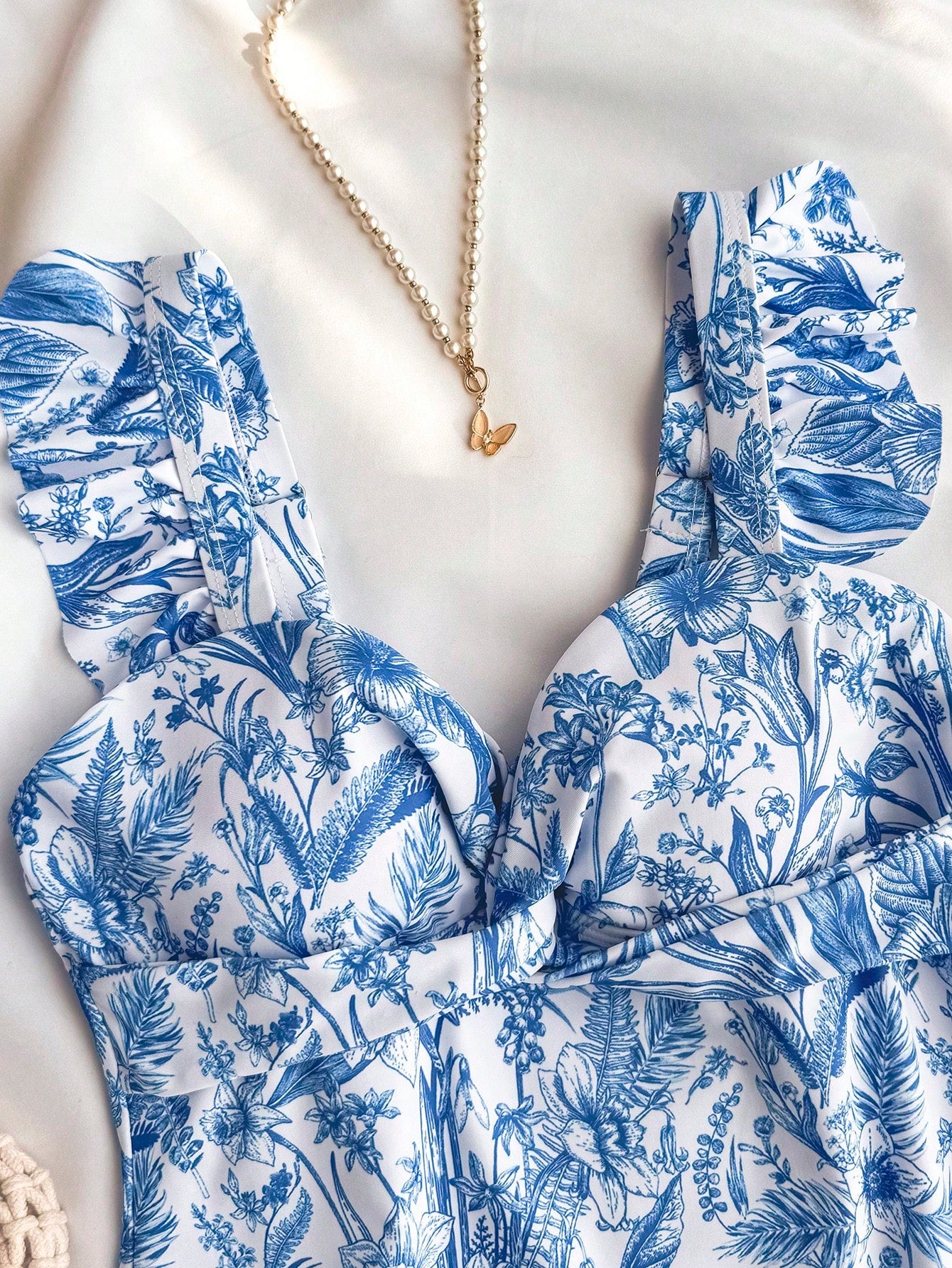 Tween girls blue and white floral print one-piece swimsuit with ruffle detail, spaghetti straps, V-neck styling, and vacation beachwear look.