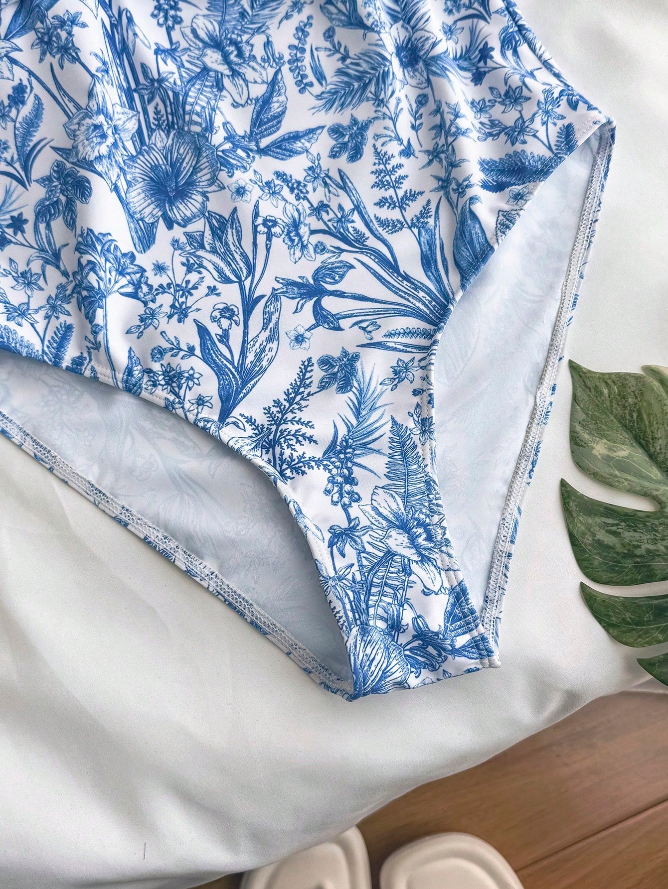 Tween girls blue and white floral print one-piece swimsuit with ruffle detail, spaghetti straps, V-neck styling, and vacation beachwear look.