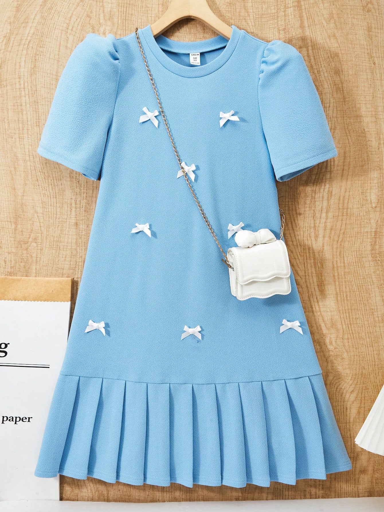 Tween girls apricot short-sleeve pleated smock dress with 3D bow decor and round neckline.