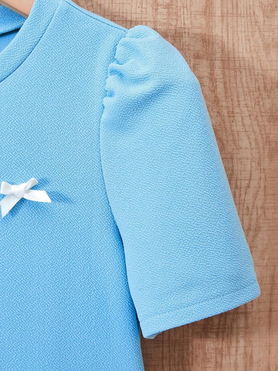 Tween girls apricot short-sleeve pleated smock dress with 3D bow decor and round neckline.