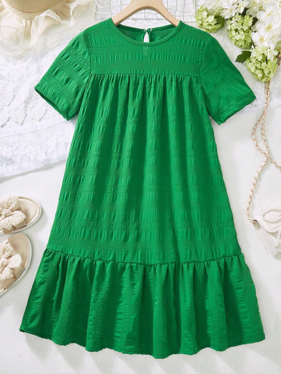 Tween girl wearing an Army Green textured short sleeve smock midi dress with round neck and ruffle flounce hem.