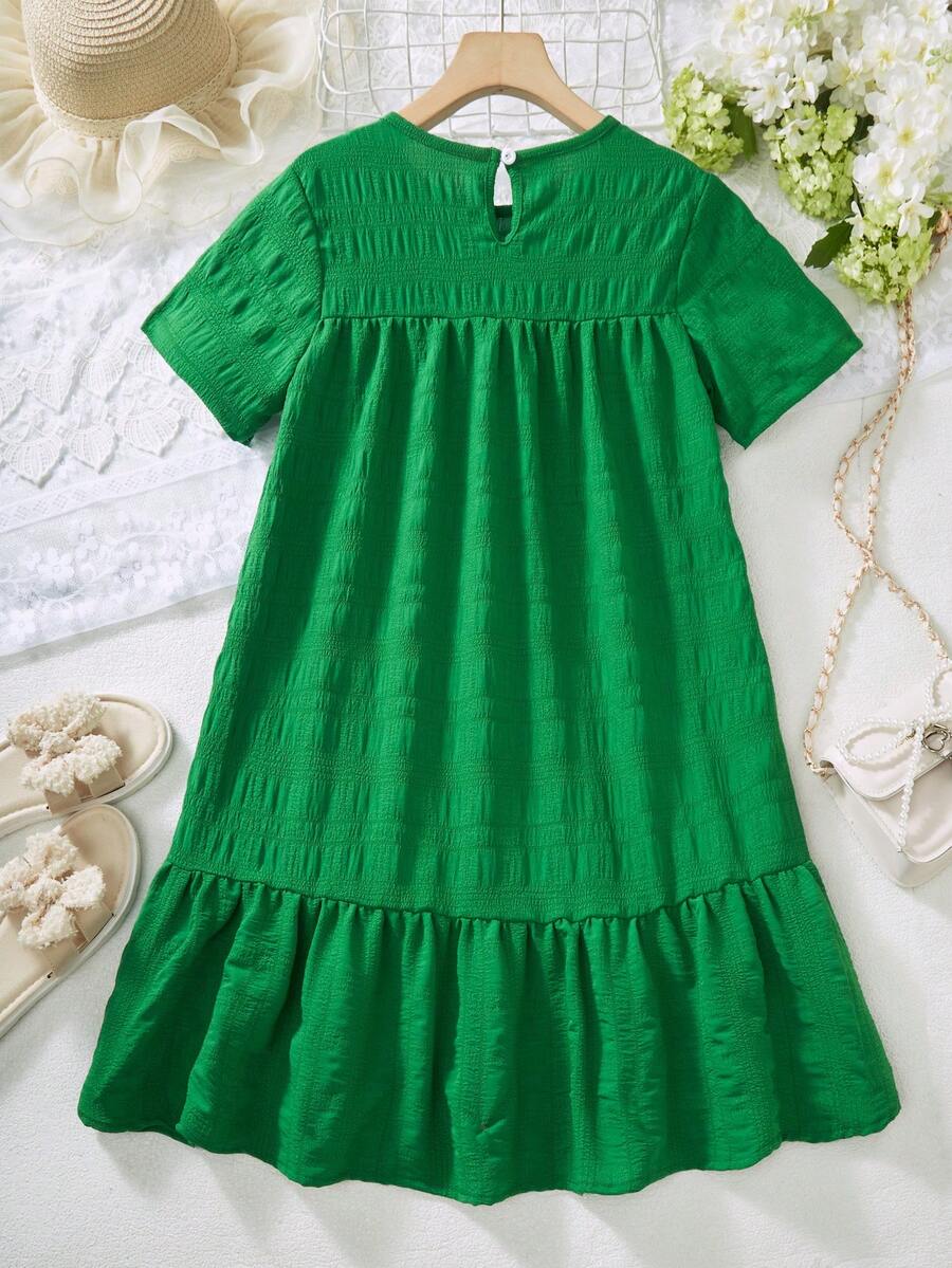 Tween girl wearing an Army Green textured short sleeve smock midi dress with round neck and ruffle flounce hem.