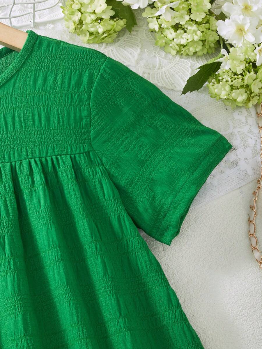 Tween girl wearing an Army Green textured short sleeve smock midi dress with round neck and ruffle flounce hem.