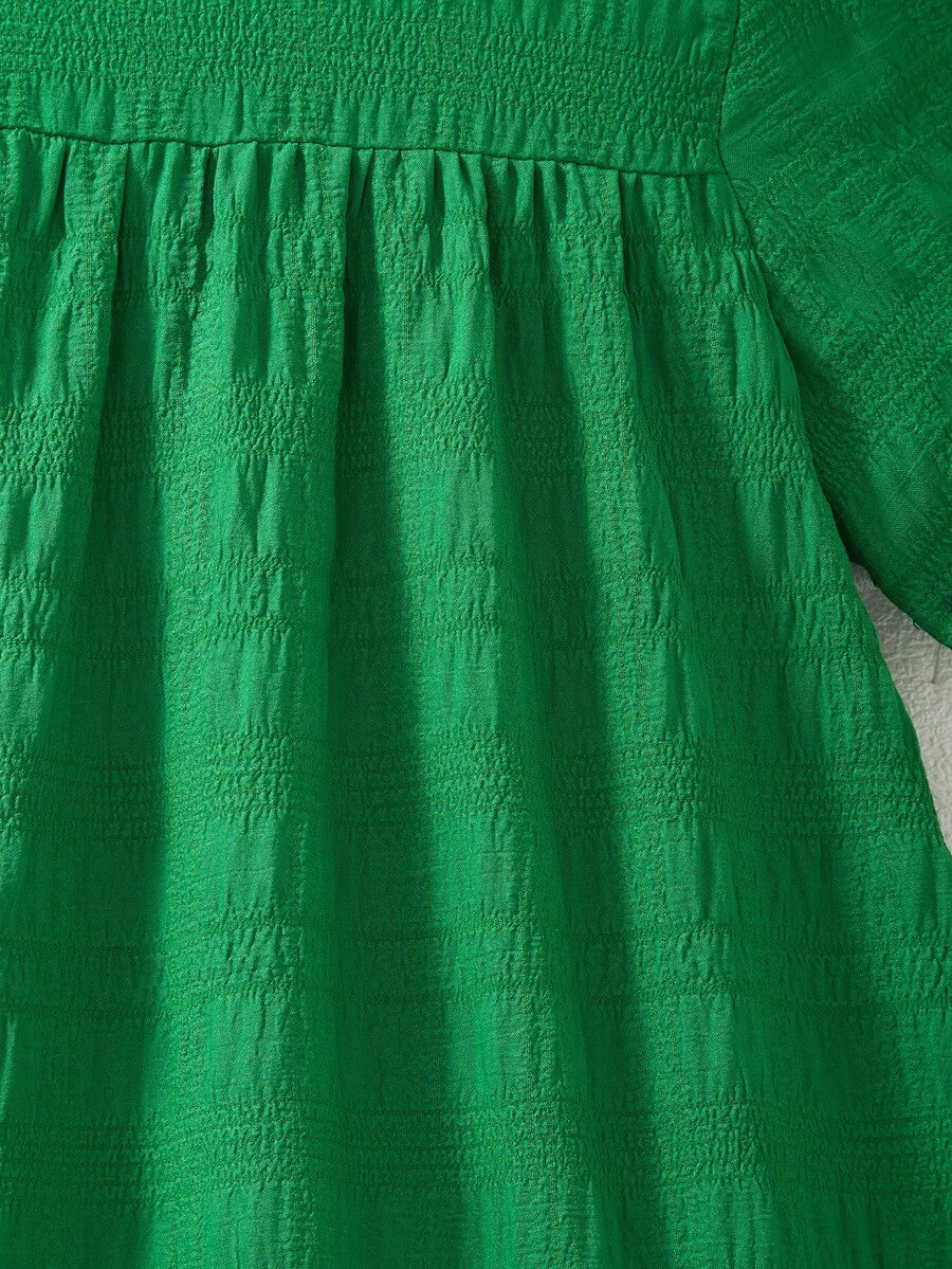Tween girl wearing an Army Green textured short sleeve smock midi dress with round neck and ruffle flounce hem.