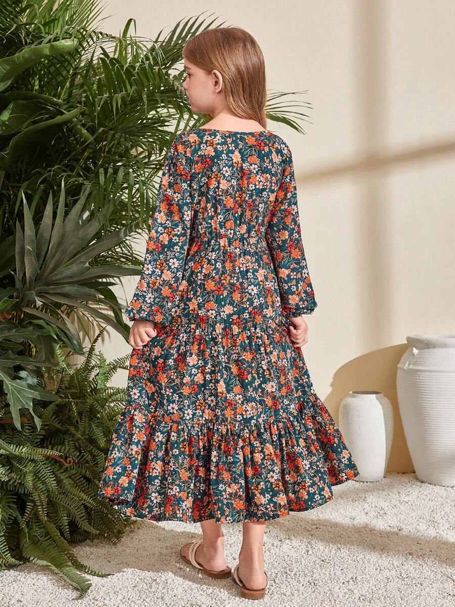 Tween girl wearing an apricot ditsy floral V-neck midi dress with long bishop puff sleeves, tiered ruffle layers, and a flounce hem.