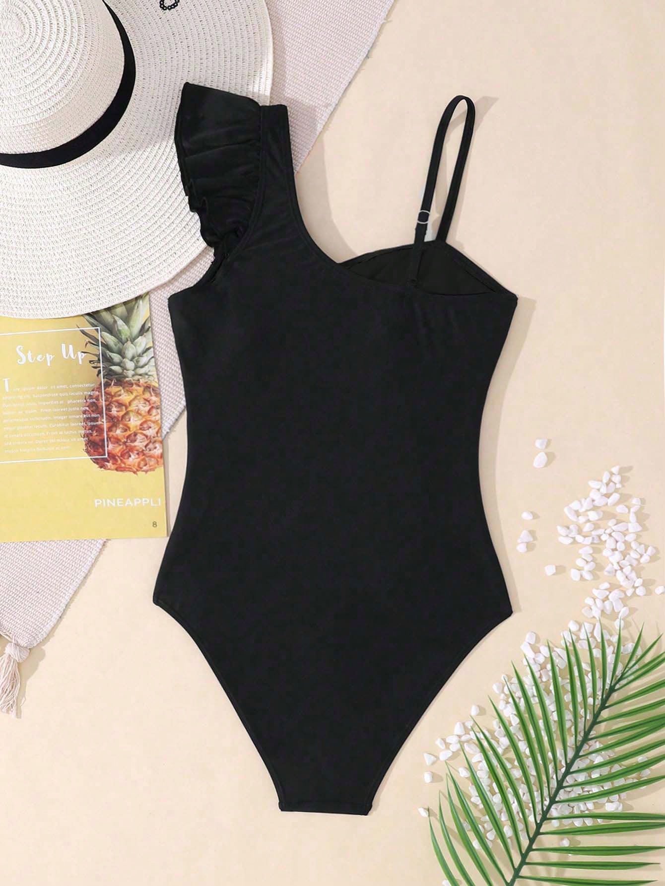Tween girl one-piece swimsuit in brown polka dot geometric print with asymmetrical neckline, ruffle detail, cut-out design, and fitted mid-waist swim bottom.