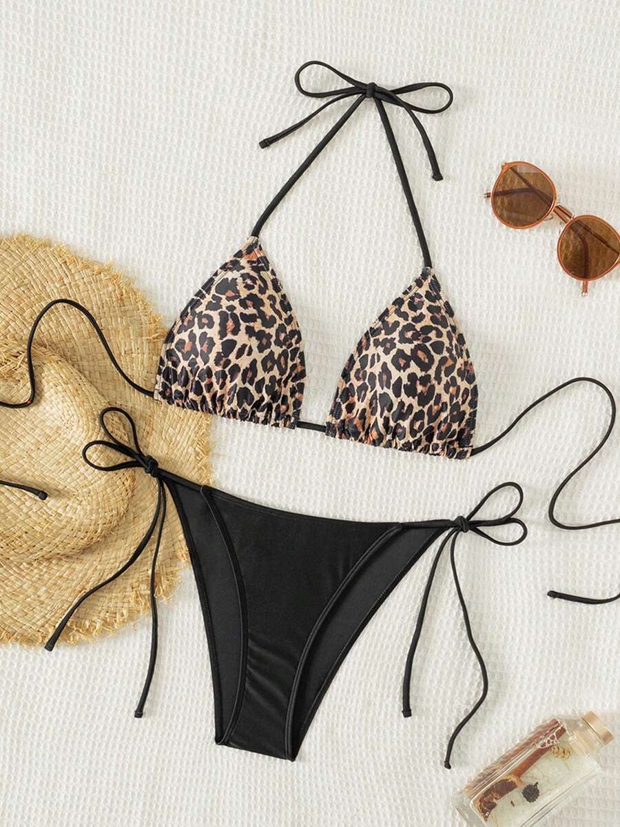 Women's black two-piece bikini set featuring a halter neck with a colorful sun pendant, triangle cups, and high-cut tie-side bottoms.