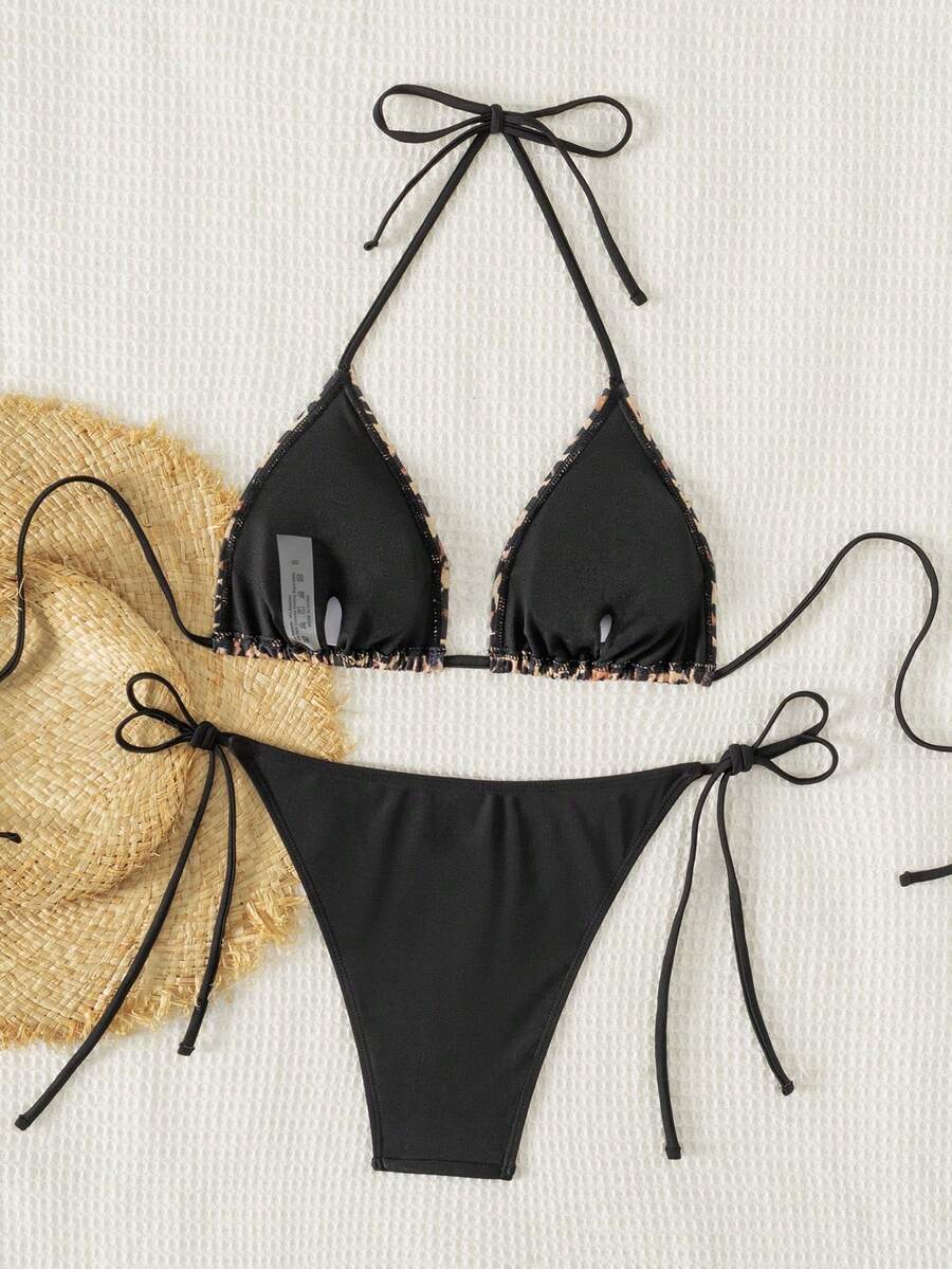 Women's black two-piece bikini set featuring a halter neck with a colorful sun pendant, triangle cups, and high-cut tie-side bottoms.