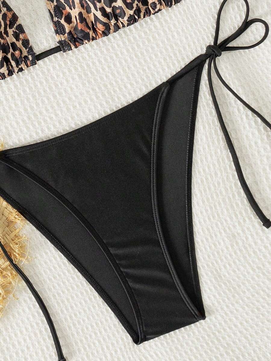 Women's black two-piece bikini set featuring a halter neck with a colorful sun pendant, triangle cups, and high-cut tie-side bottoms.
