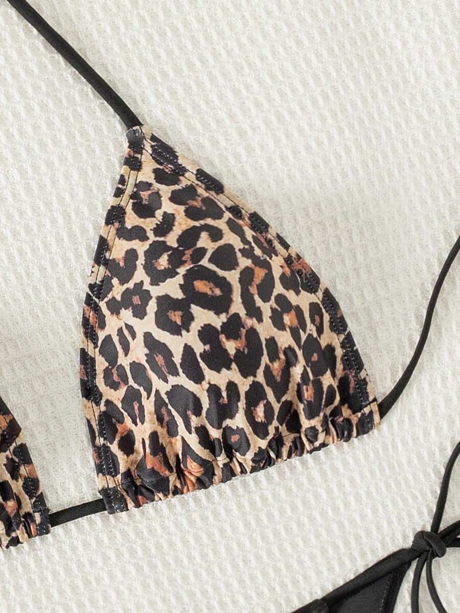 Women's black two-piece bikini set featuring a halter neck with a colorful sun pendant, triangle cups, and high-cut tie-side bottoms.