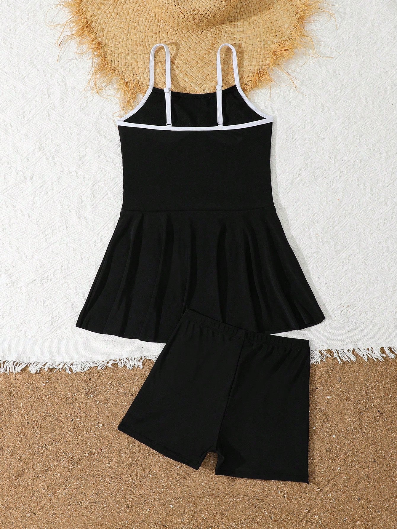 Tween girls black two-piece tankini swimwear set featuring a spaghetti strap sleeveless top with cutout detail and contrast piping, paired with short swim shorts.
