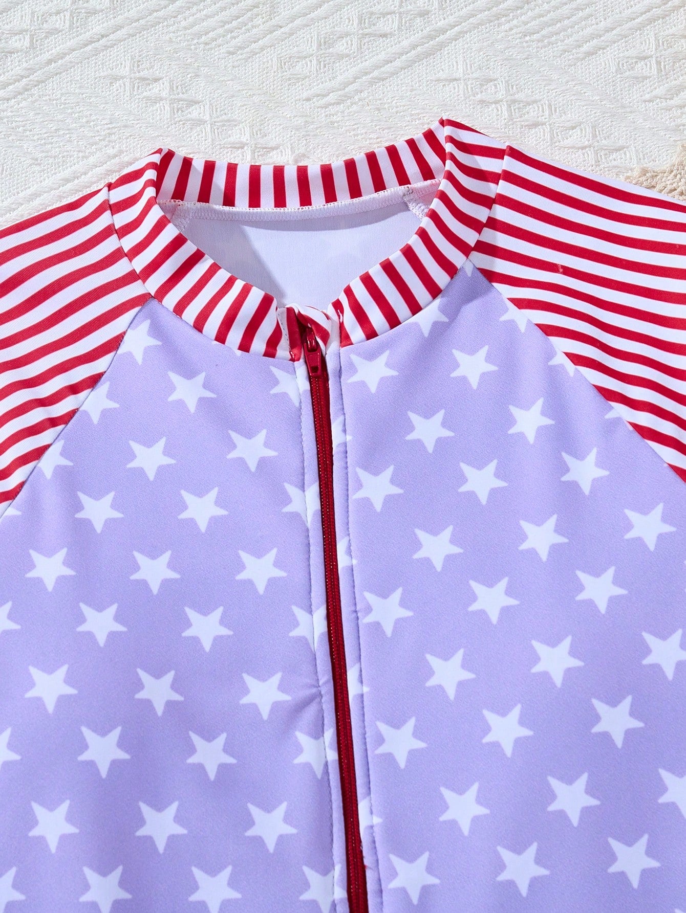 Multicolor tween girls one-piece swimsuit with striped and star patchwork design, high neck, ruffle details, zipper and button accents.