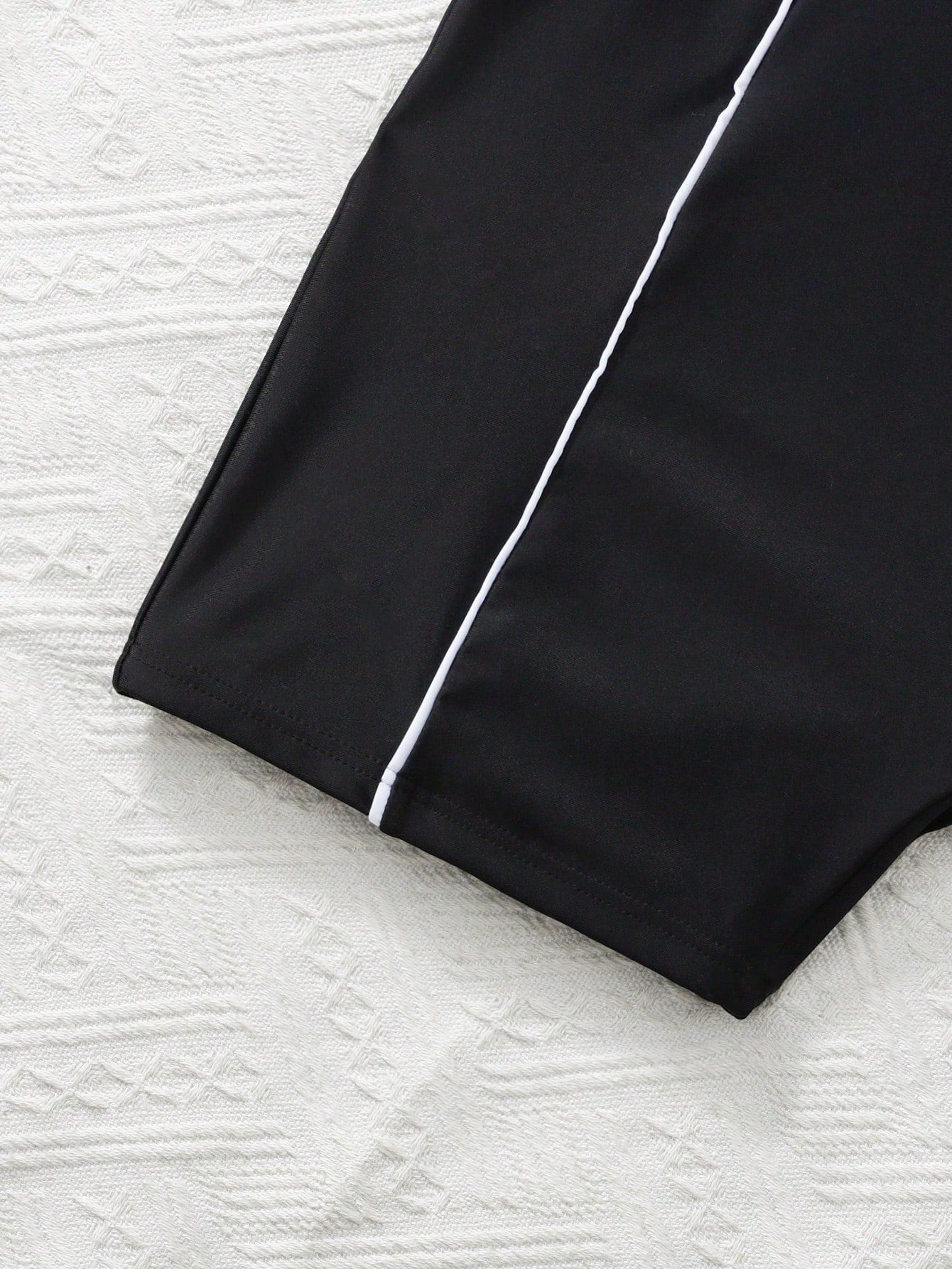 Black and white one-piece rashguard swimsuit for tween girls with short sleeves, high neck, zipper detail, fitted shape, and shorts-style bottom.