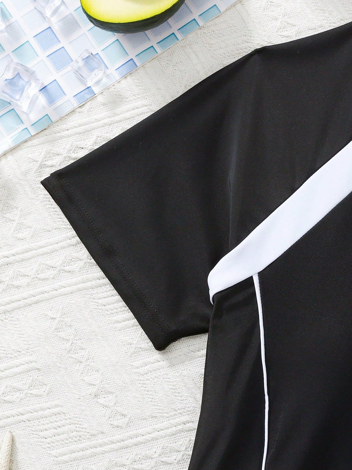 Black and white one-piece rashguard swimsuit for tween girls with short sleeves, high neck, zipper detail, fitted shape, and shorts-style bottom.
