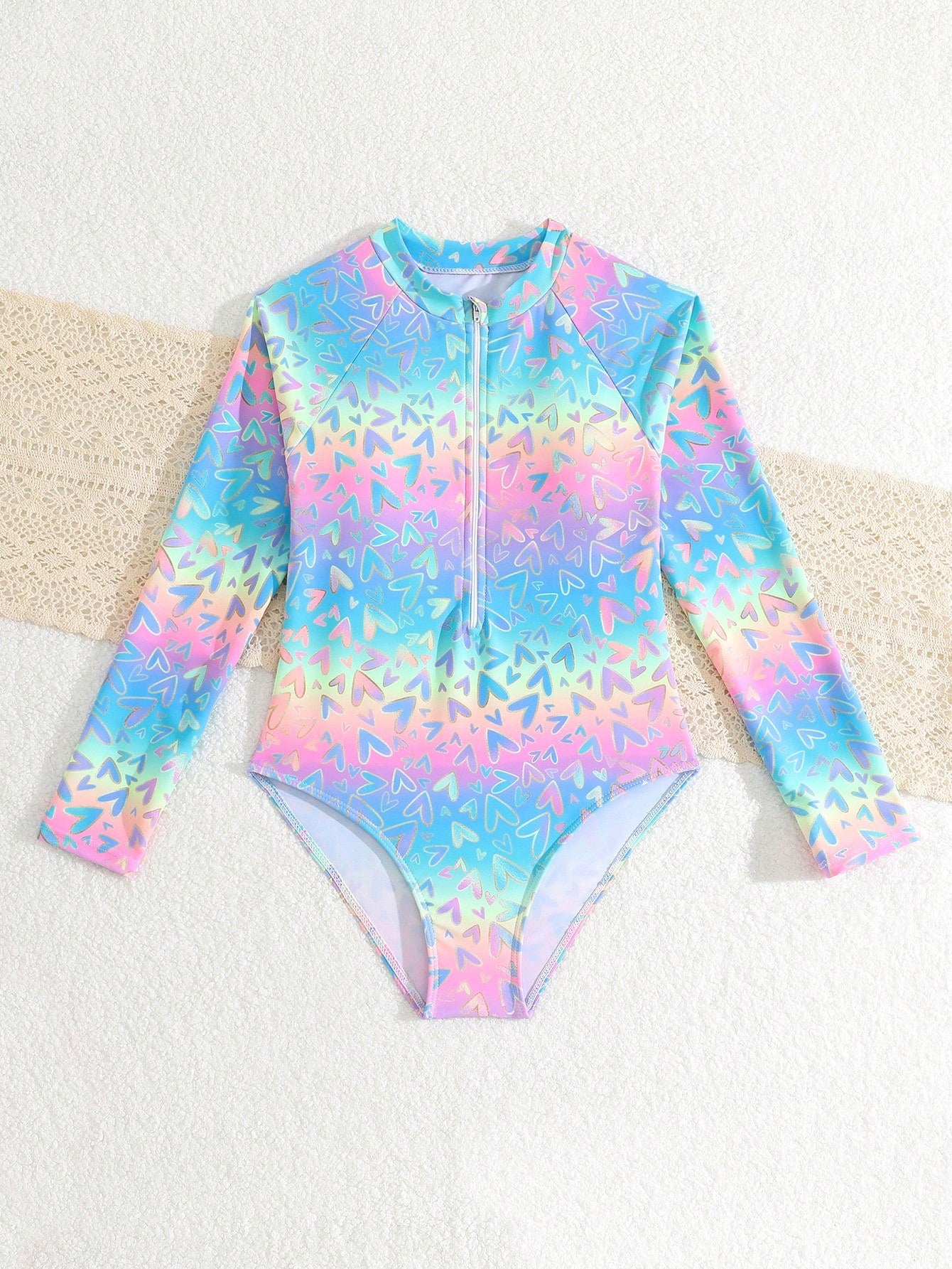 Tween girls one-piece rash guard swimsuit with long sleeves, high neck, front zipper, and ocean shell graphic print in a fitted style for beach, swimming, and vacation wear.
