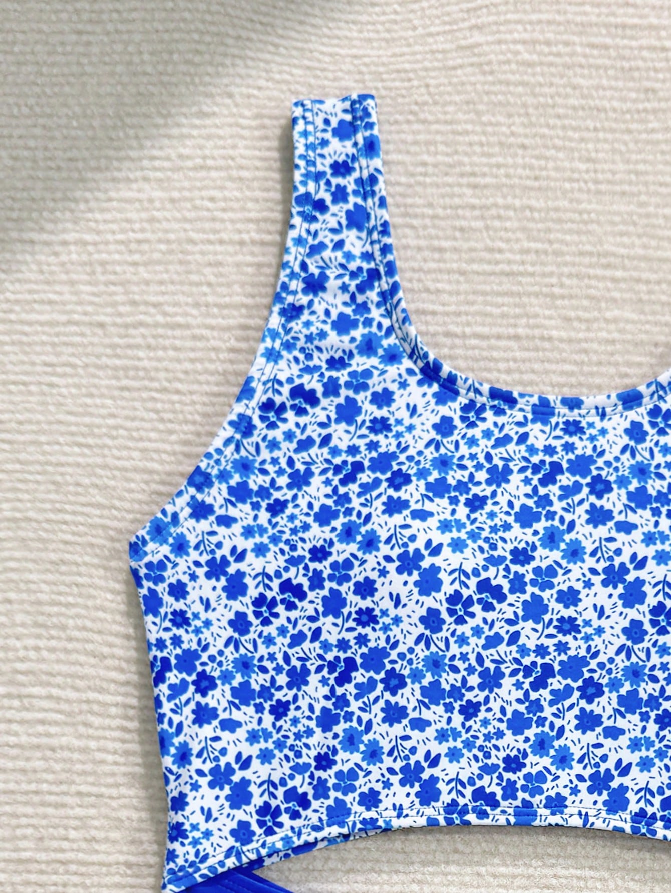 Tween girls blue and white floral one-piece swimsuit with scoop neck, cut-out detail, lined body, and high-stretch fabric for beach and vacation wear.