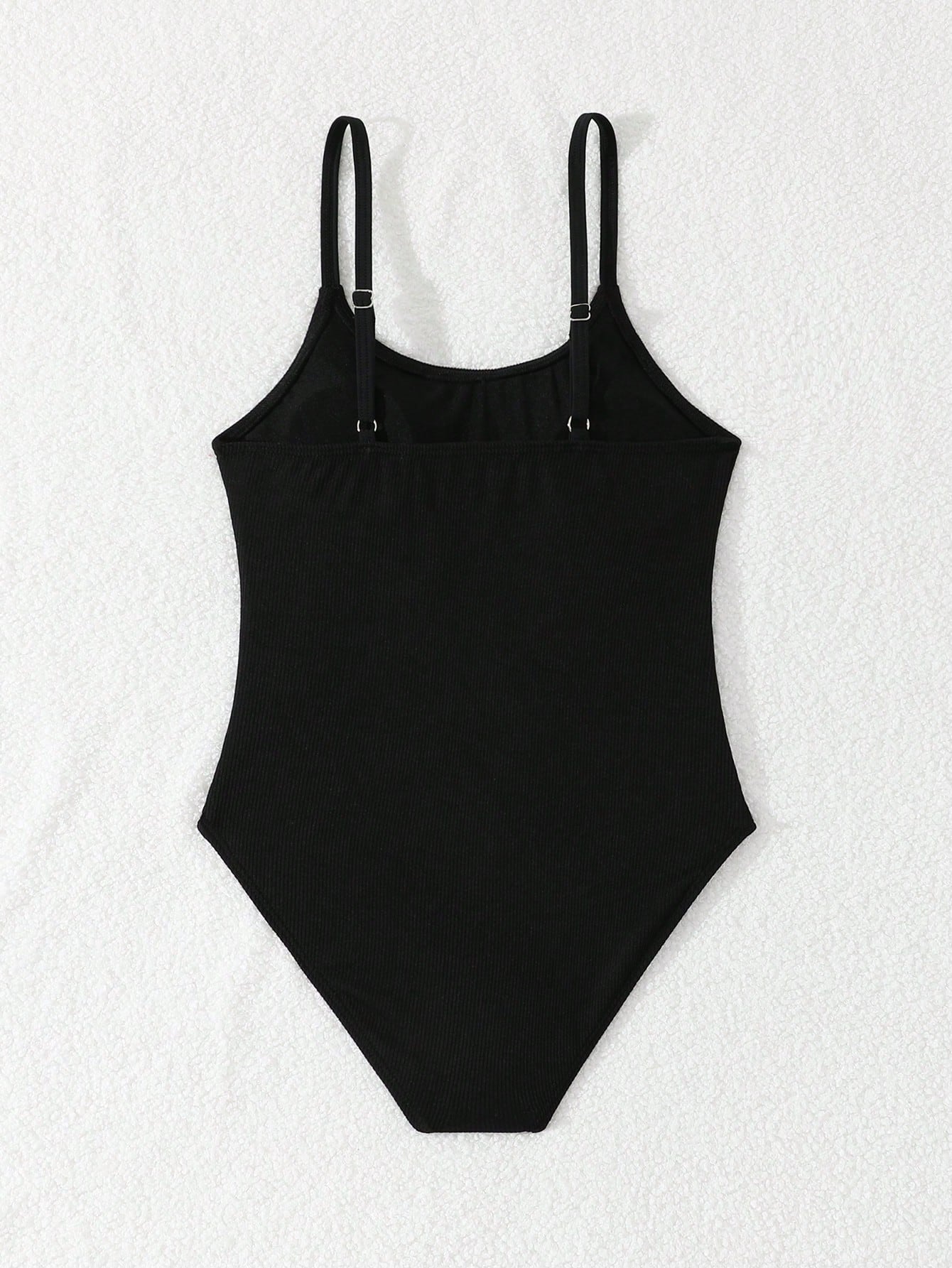 Tween girls' black rib knit one-piece swimsuit with spaghetti straps, plain textured fabric, short length, and vacation swimwear style.