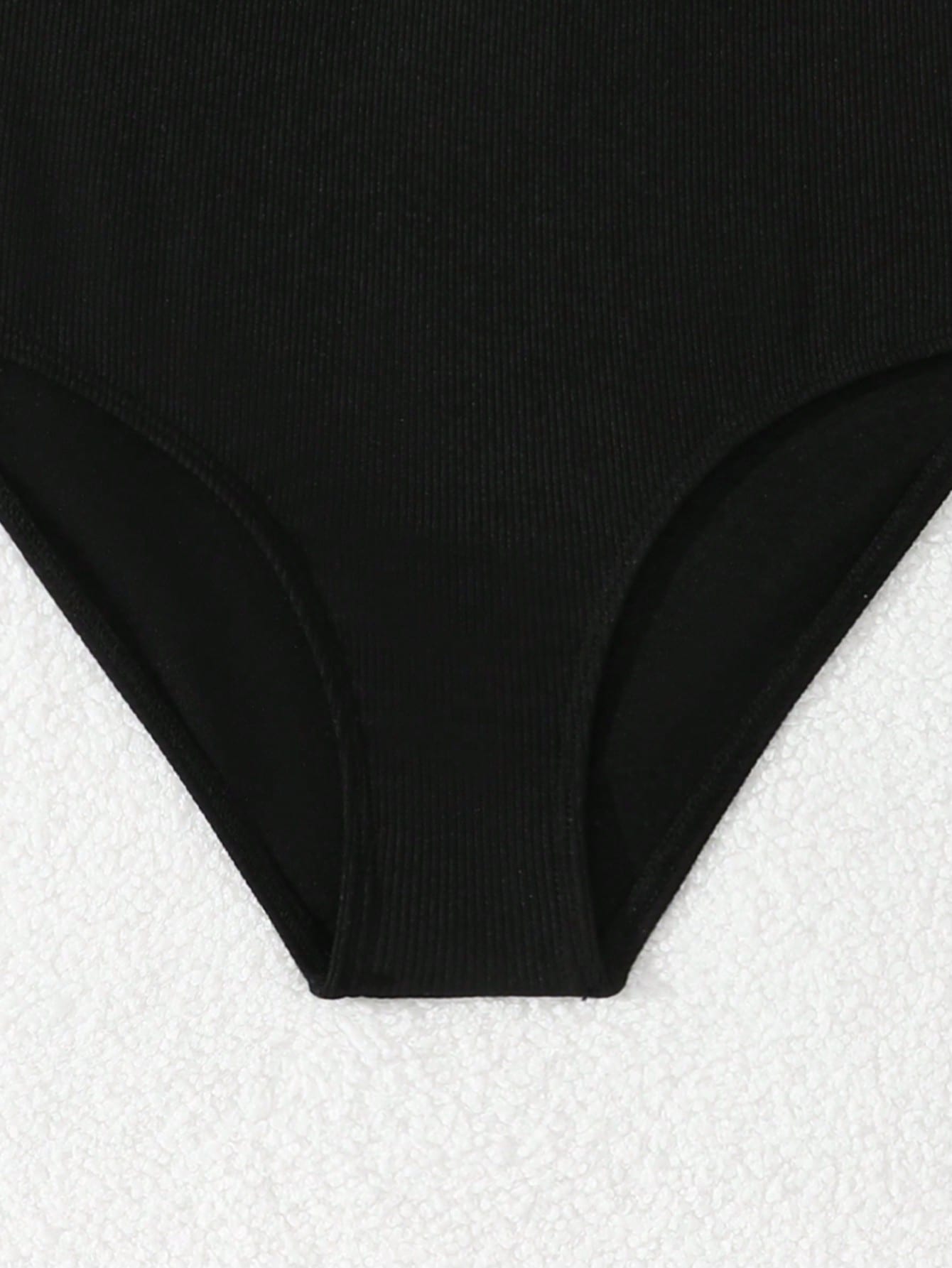 Tween girls' black rib knit one-piece swimsuit with spaghetti straps, plain textured fabric, short length, and vacation swimwear style.