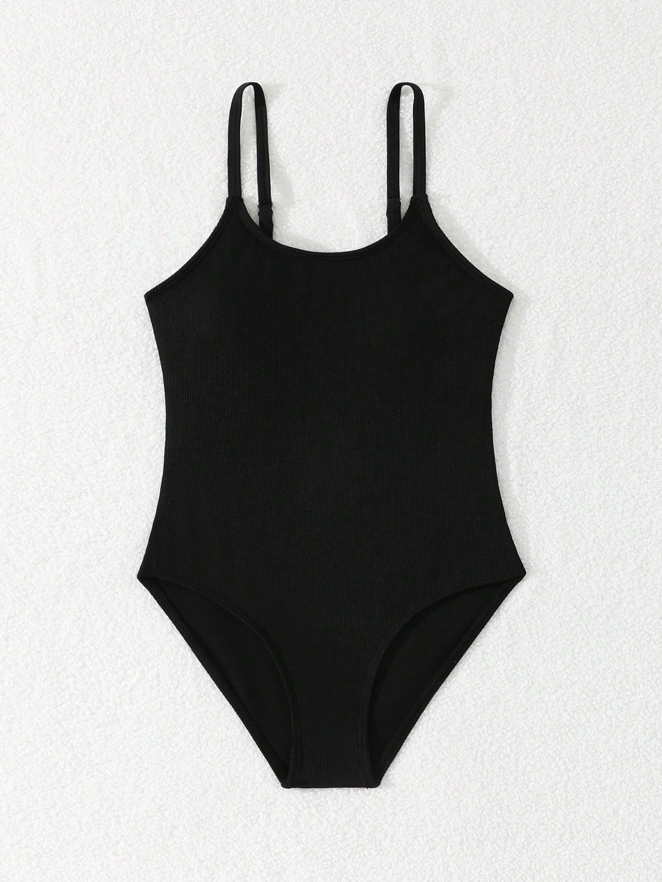Tween girls' black rib knit one-piece swimsuit with spaghetti straps, plain textured fabric, short length, and vacation swimwear style.