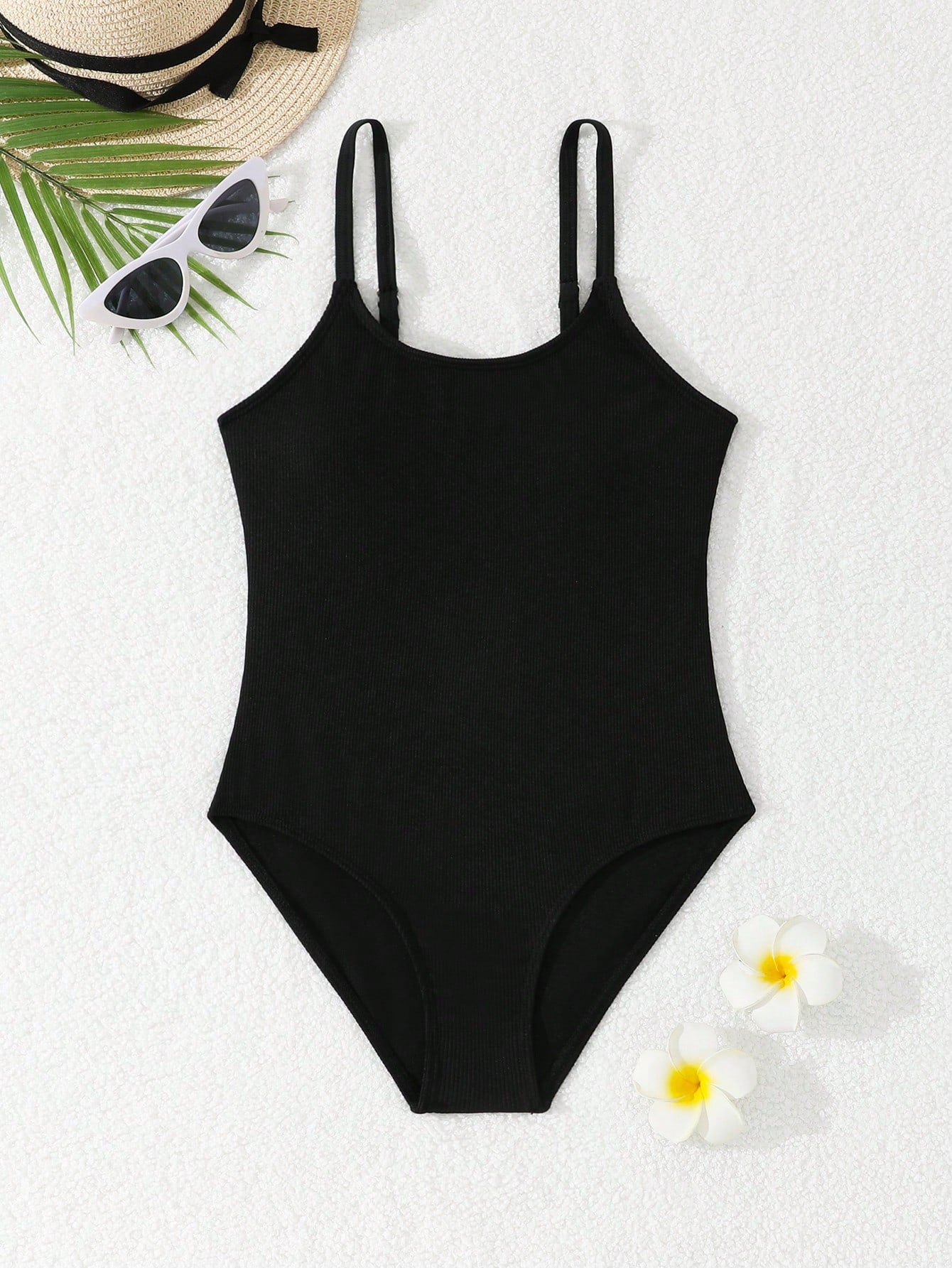 Tween girls' black rib knit one-piece swimsuit with spaghetti straps, plain textured fabric, short length, and vacation swimwear style.